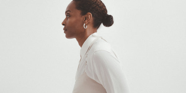 side profile of a model wearing a white shirt with a pale pink top layered over it