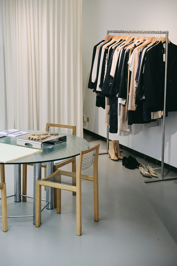 photo of the enso store in amsterdam, featuring a metal wavy chais, grey floor and a vitrine in the back with accessories and bags